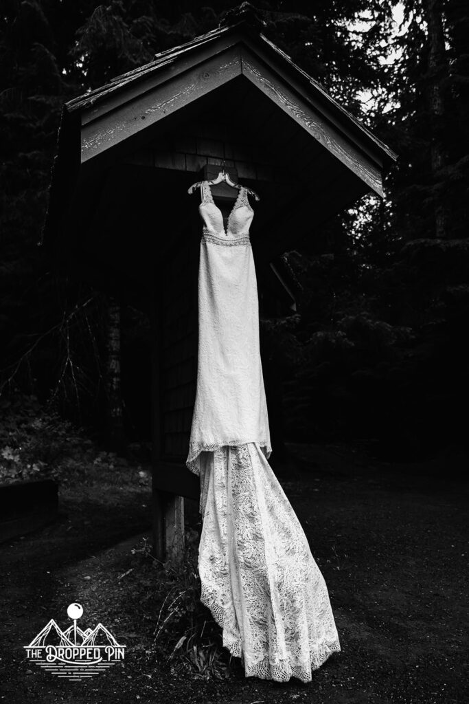 A bridal dress hangs in thee forest waiting to be worn during this Washington elopement