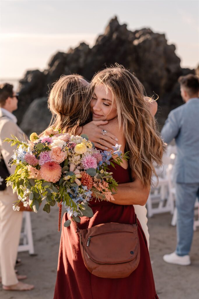A bride embraces one of her guests at her coastal elopement. 