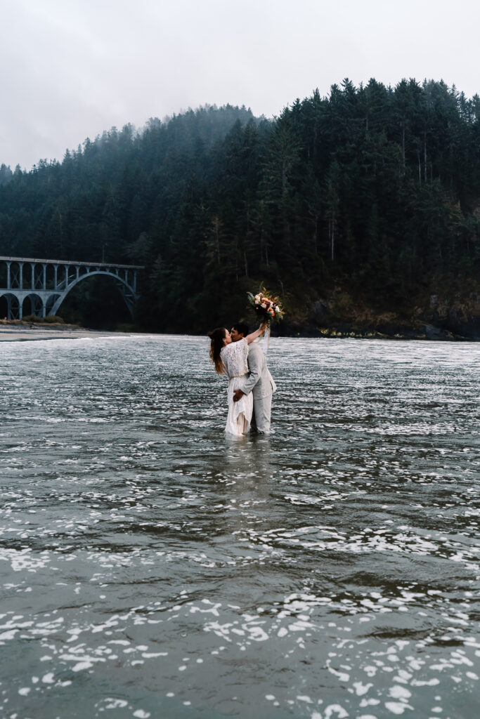 As the tide rolls in and the icy waters roll over them, the couple from this surfer wedding remains embraced, not caring that the water has risen to their knees.