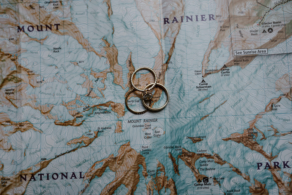 Wedding bands sit ontop of a Mt. Rainier map for this couples Mt Rainier wedding