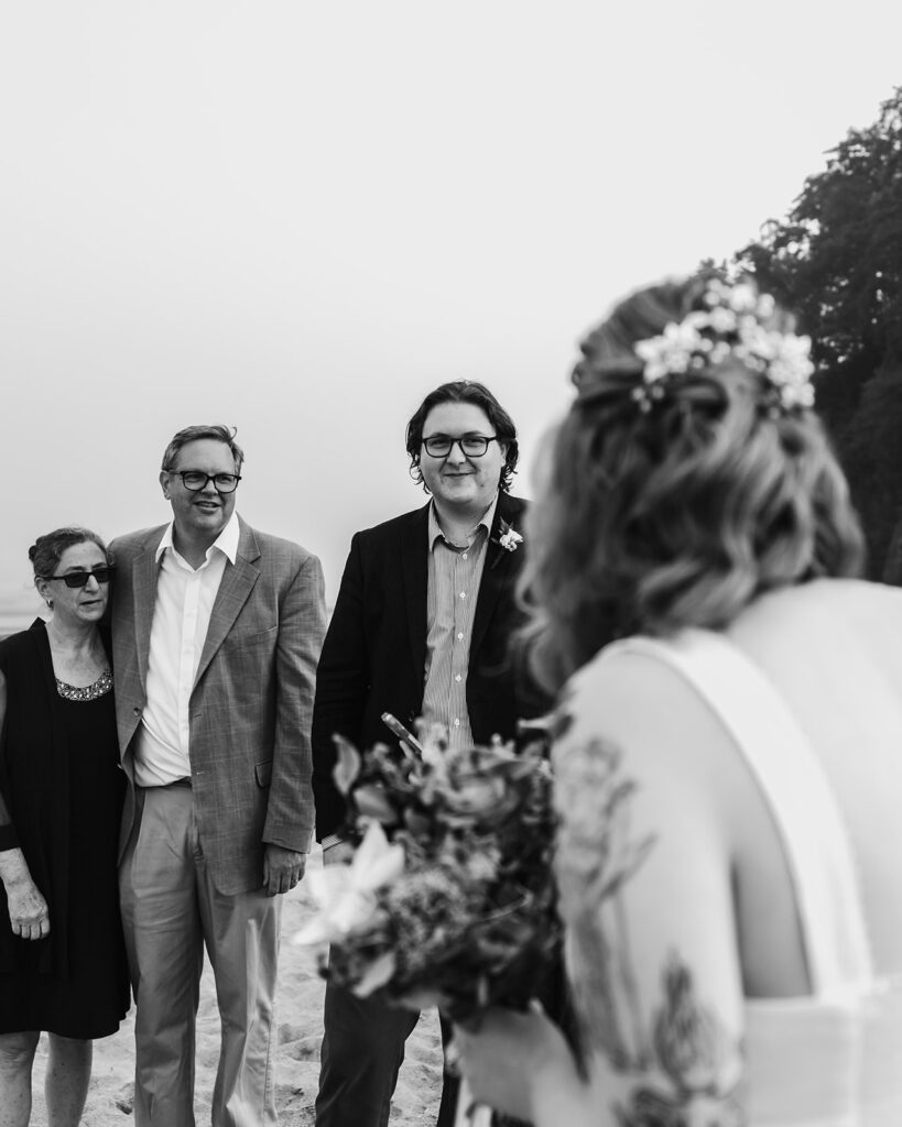 After considering elopement vs wedding, a brides perspective looking at a her groom and two guests as they exchange vows during their elopement. The back of the bride and her bouquet frame the foreground of her view. 