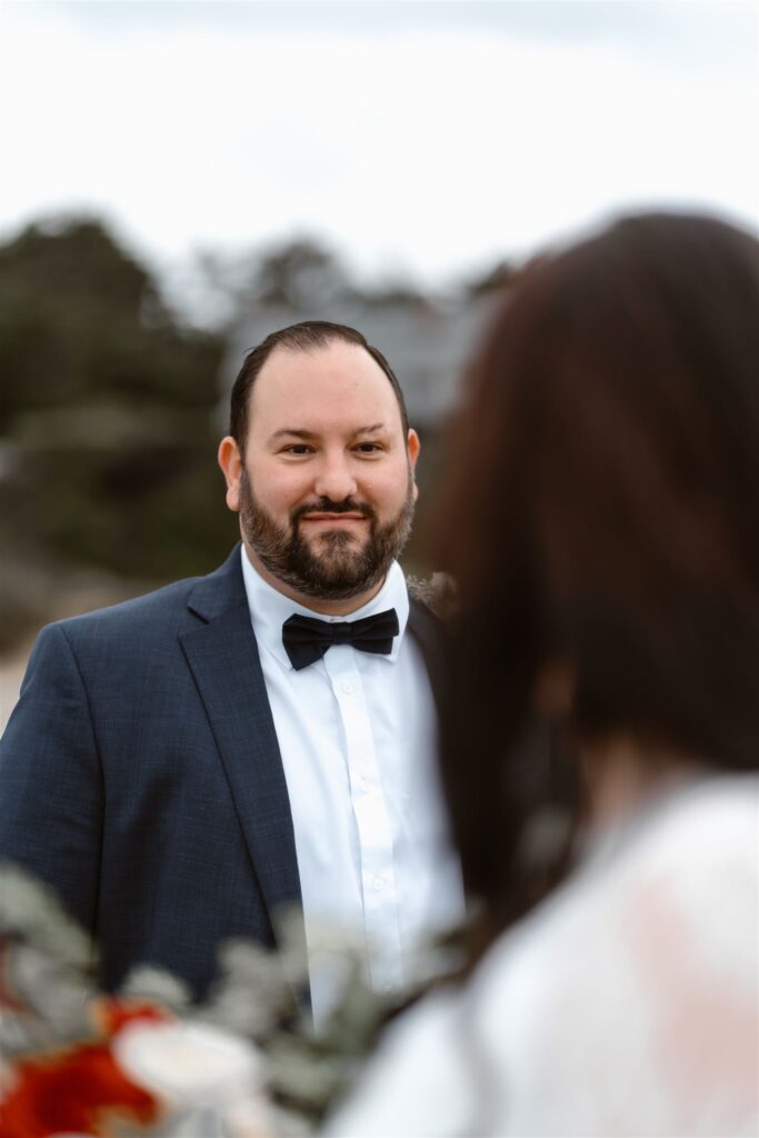 a perspective shot of a groom gazing lovingly at his bride. his face is in focus and is framed by her silhouette during their pacific coast wedding