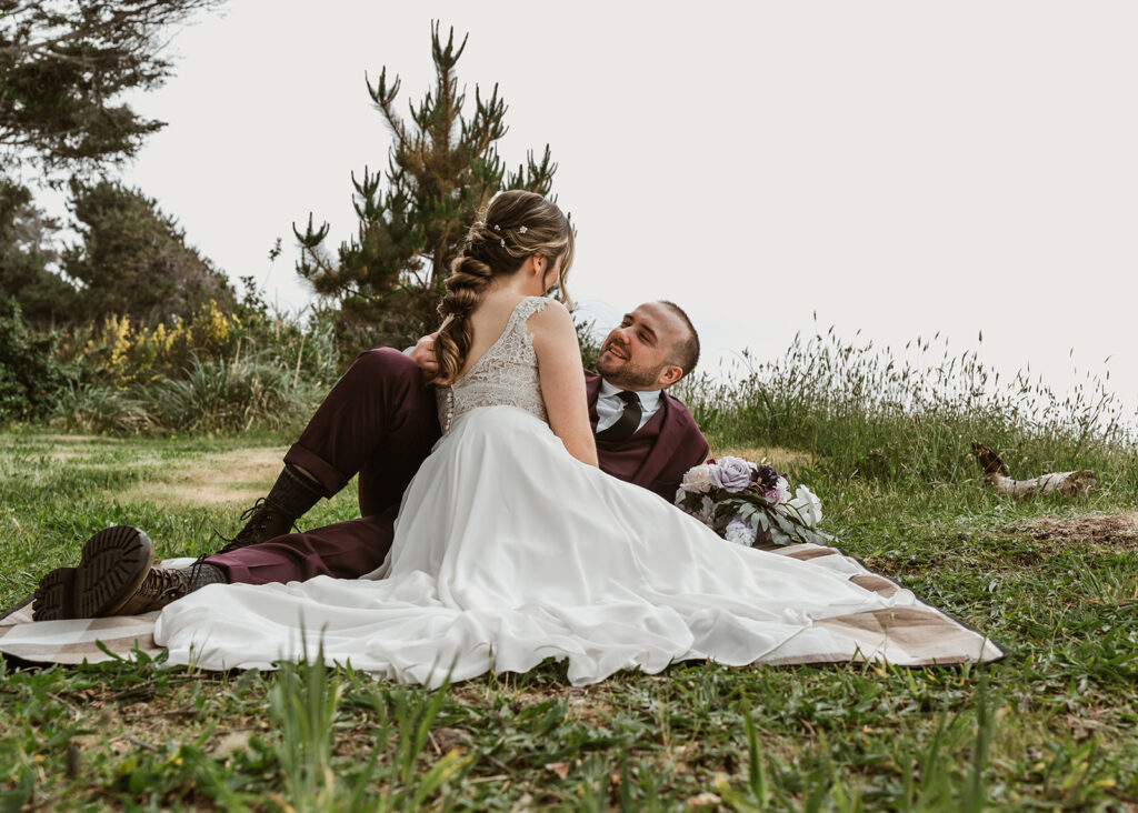 During a picnic, a bride and groom gaze lovingly at each other.