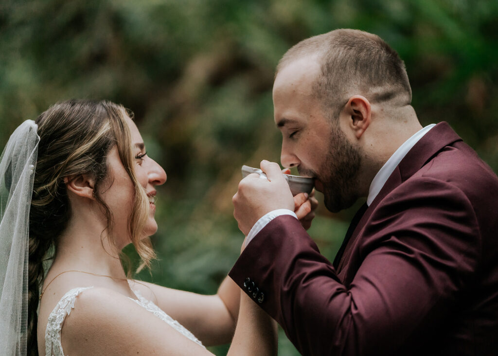 During the ceremony of their forest wedding, a couple shares a drink from a traditional Quaich.