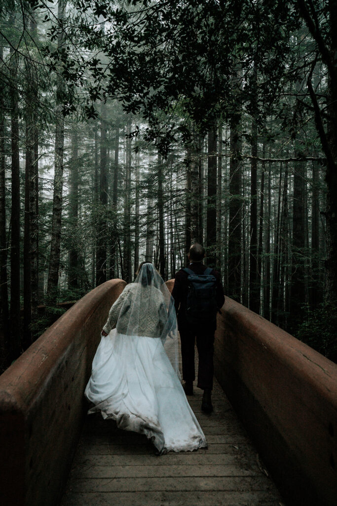 a bride runs on a wooden bridge her muddy dress floating behind her during her forest wedding
