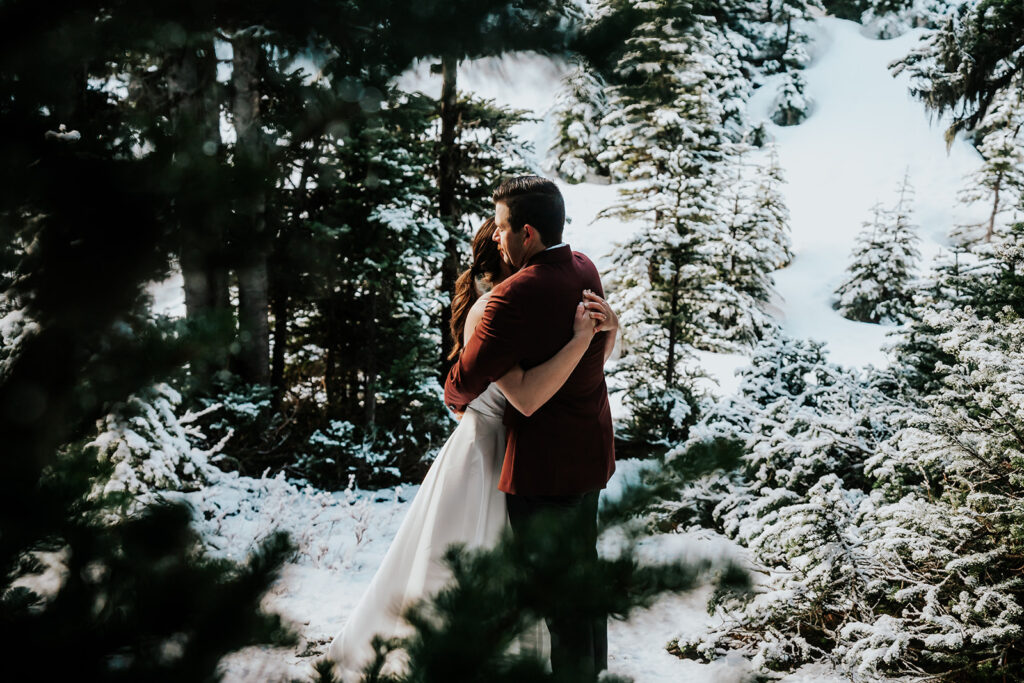 a shot taken through the trees of a couple in their wedding attire during their backpacking wedding
