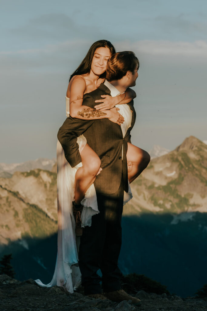 a groom carries his bride on his back during their hiking elopement