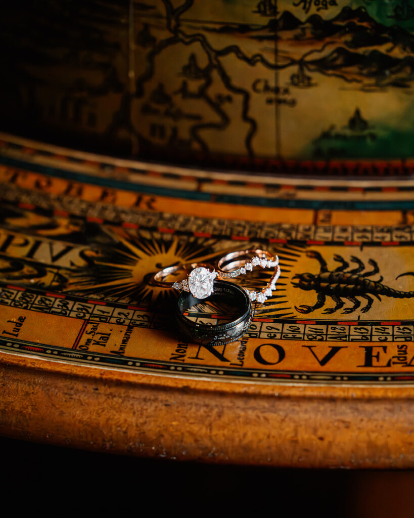 a close up shot of the wedding rings resting on a massive, vintage globe. 
