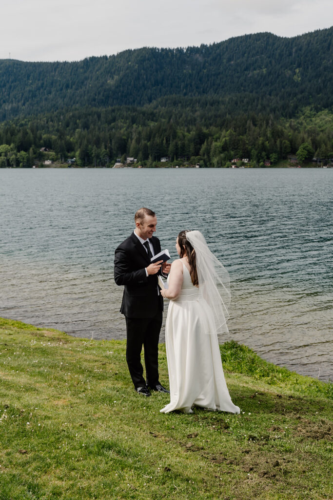 a groom reads his private vows to his bride on the green shores of lake sutherland