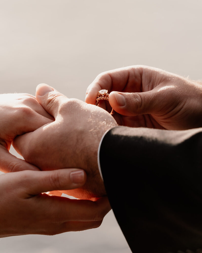 a close up shot of a groom slipping on his brides wedding ring during their lake crescent wedding 