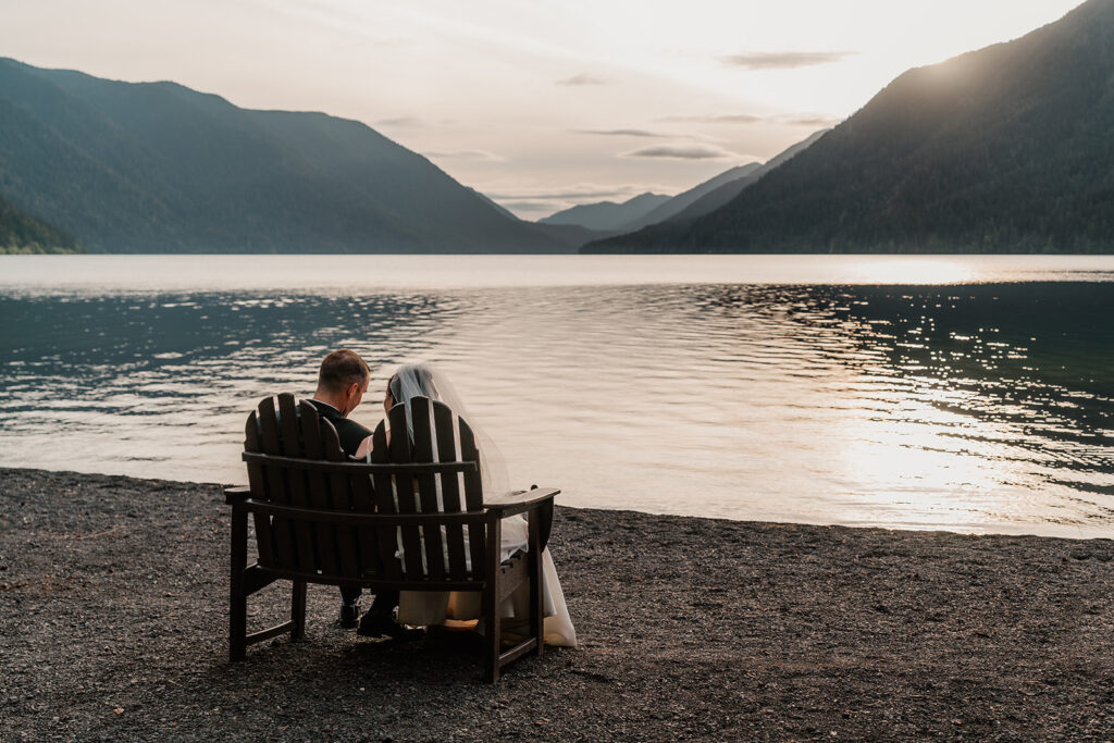 a bride and groom bask in the setting sun after their lake crescent wedding. The lake is glowing from the light of the setting sun.