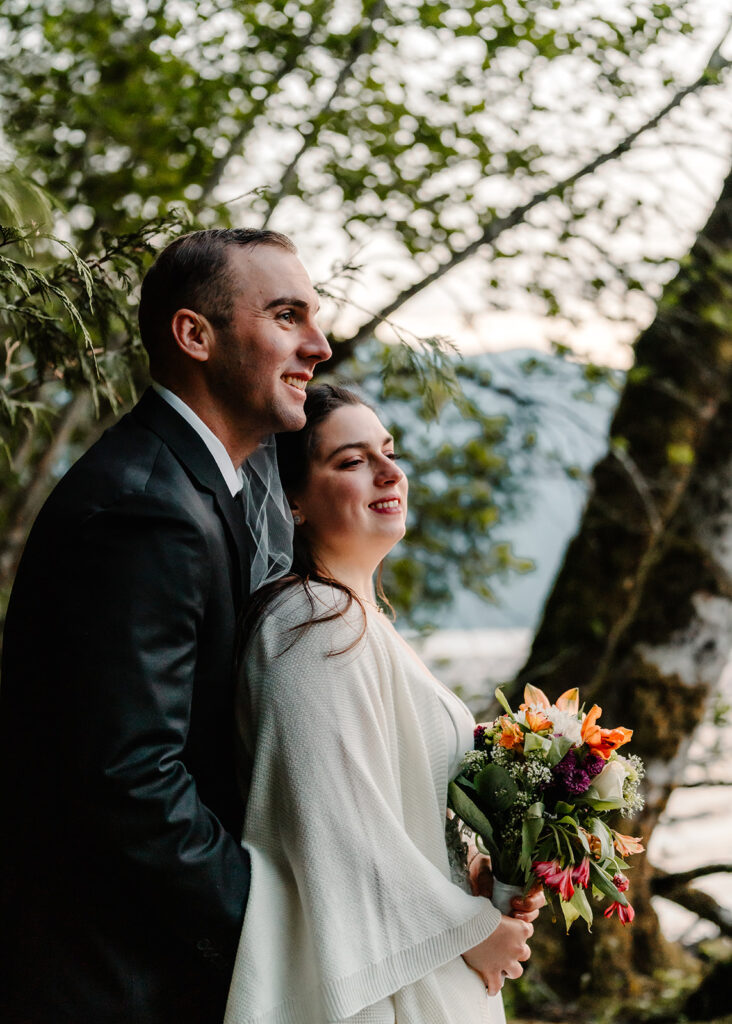 a bride and groom snuggle in the forest to end their lake crescent wedding