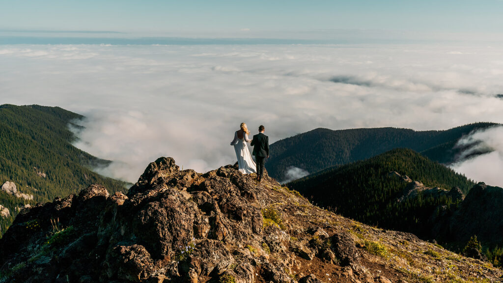 A bride and groom explre a cloud inversion below a cliff during their Olympic Peninsula elopement. 