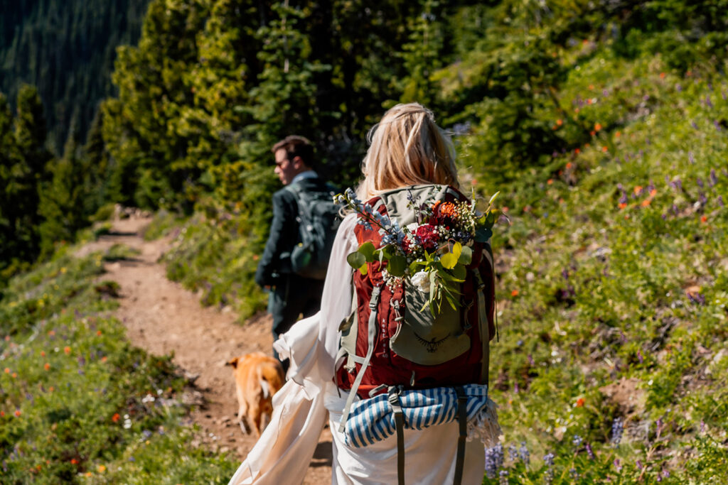 a close up of the brides bright bouquet (that she made herself) fastened to her backpack