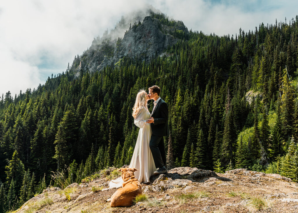 a bride and groom kiss with pines rising above during their Olympic Peninsula elopement. 