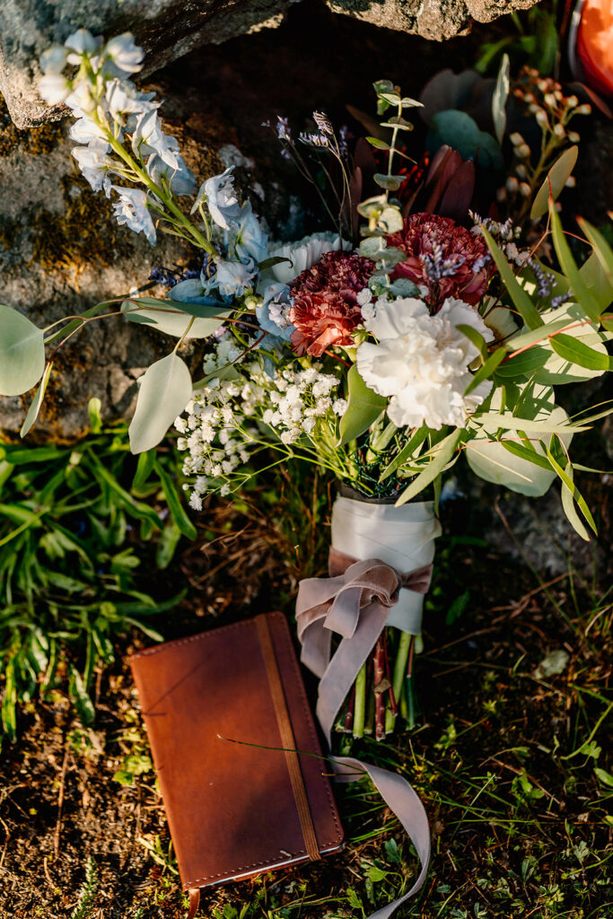a detail shot of a bright bouquet and a leather vow book from this Olympic Peninsula elopement. 