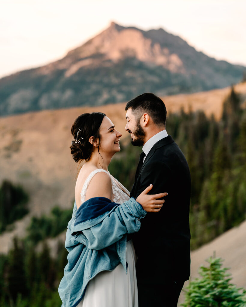a bride and groom smile at each other in front of a beautiful mountain during their Olympic National Park elopement