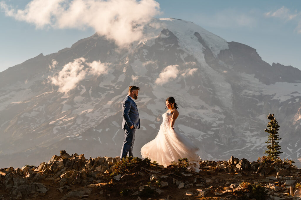 a bride twirls and shows off her dress to her groom in front of a staggering mount rainier one of the best places to elope in Washington