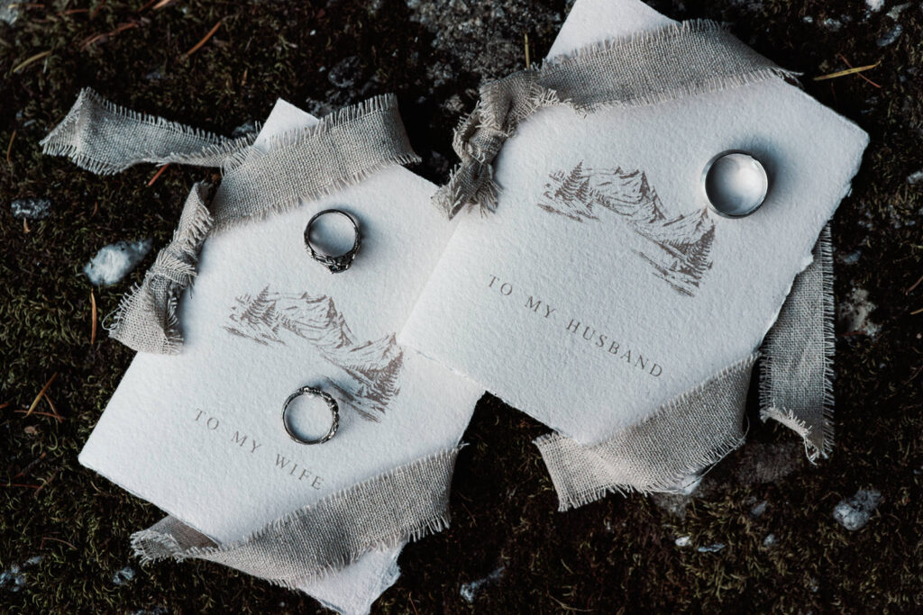 a close up shot of delicate, paper vow books and intricately designed rings 