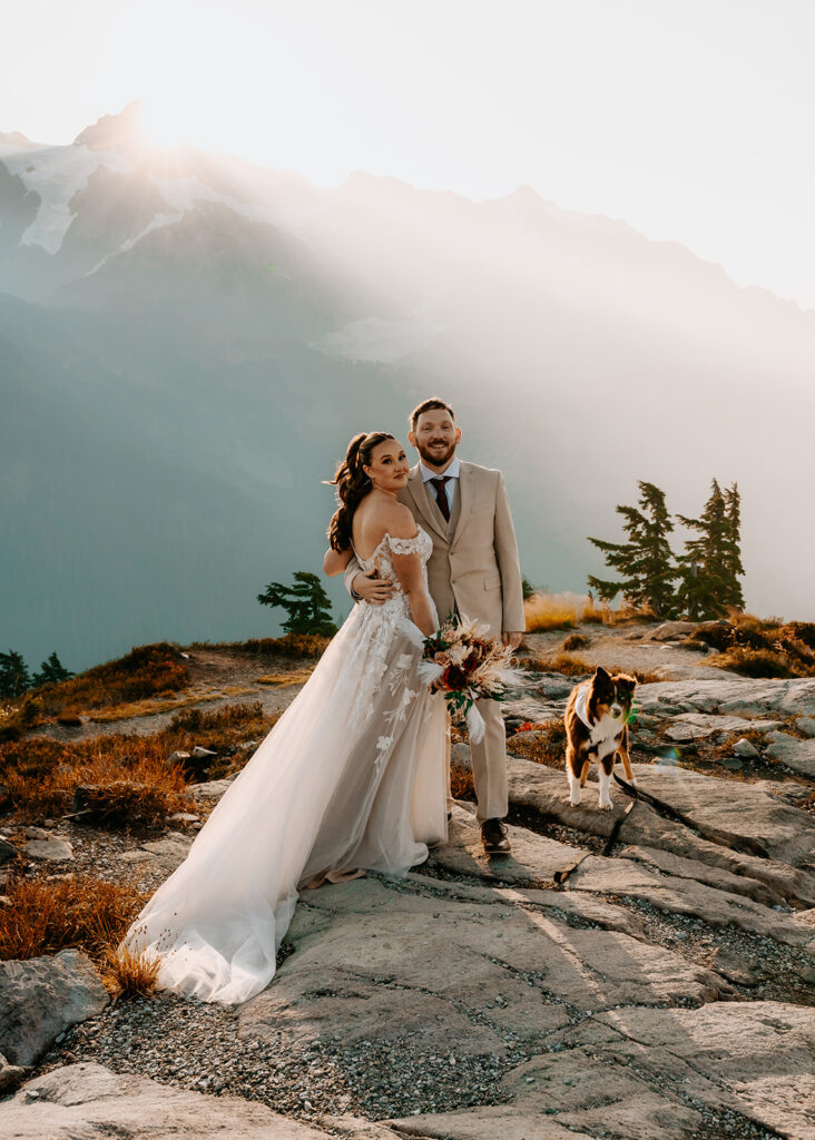 a couple in their wedding attire are softly highlighted by the morning light in the mountains 