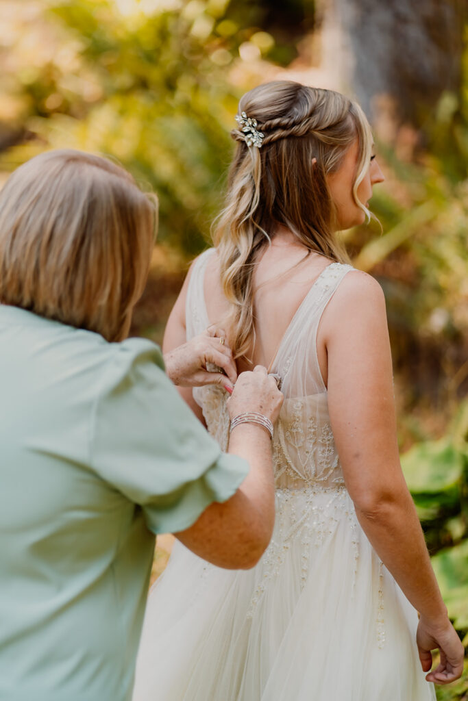 a brides mom buttons the back of her dress, helping her get ready for her mt baker micro wedding 