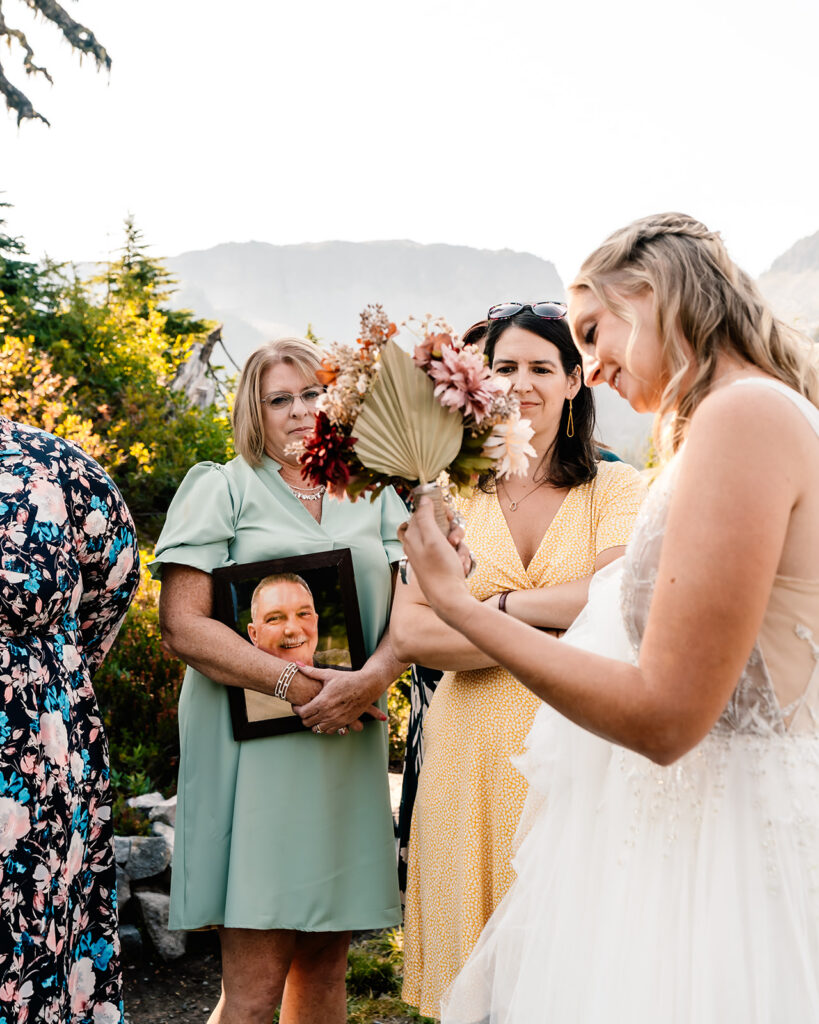 a bride shows off her wedding bouquet to her guests as they gather for their mt baker micro wedding 