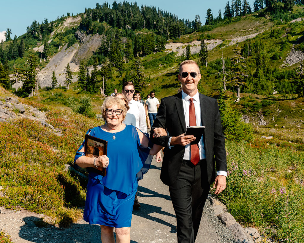 guests smile widely at the camera as they walk towards the ceremony location for this mt baker micro wedding