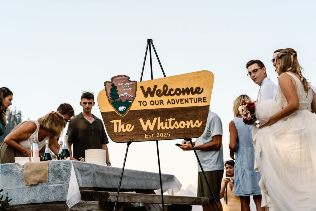 a sign reading "welcome to our adventure the Whitsons Est 2025 in a park sign style serves as the welcome to their casual celebration