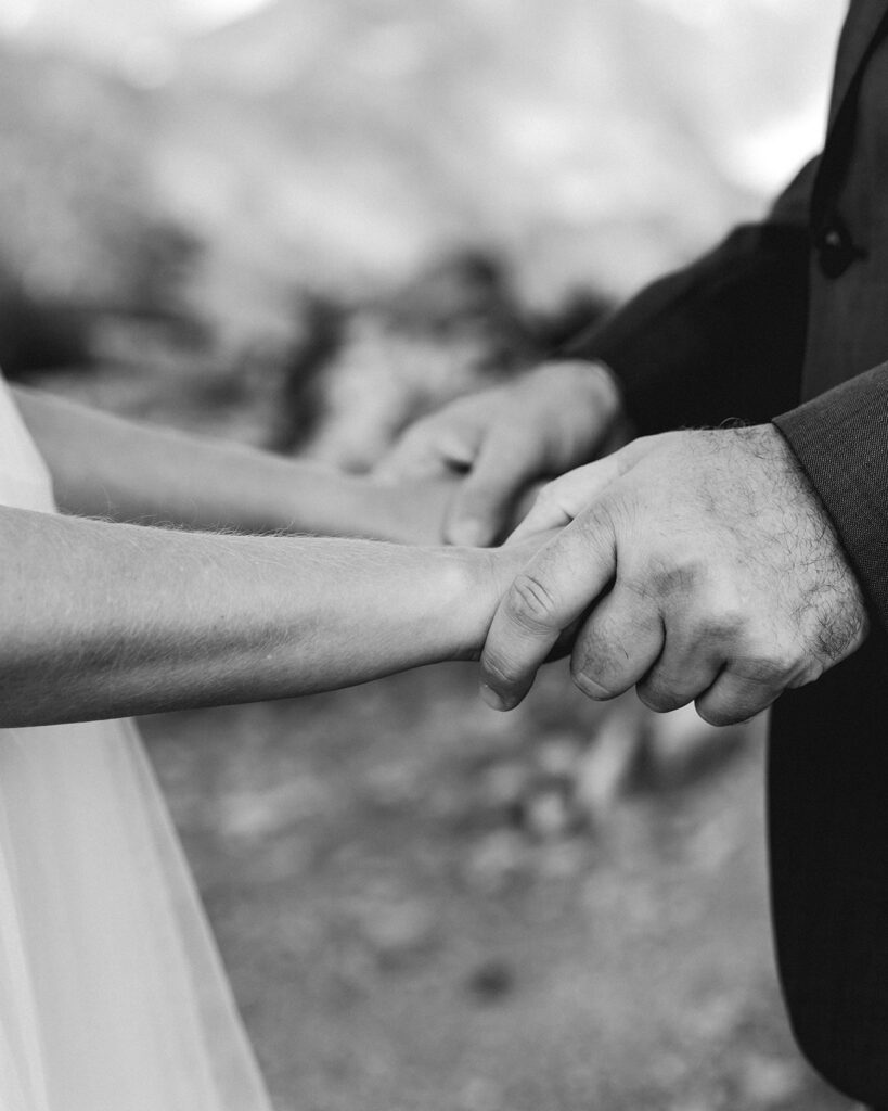 a black and white close up image of a bride and grooms hands clasping 
