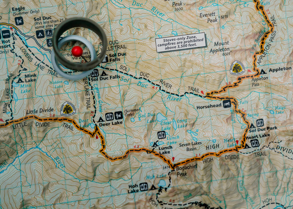 the map of the sol duc rainforest trail with a red location pin and wedding bands resting around it 