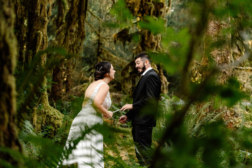 captured through the verdant foliage, we see a couple in their wedding attire laughing and smiling as they exchange vows during their hoh rainforest elopement 