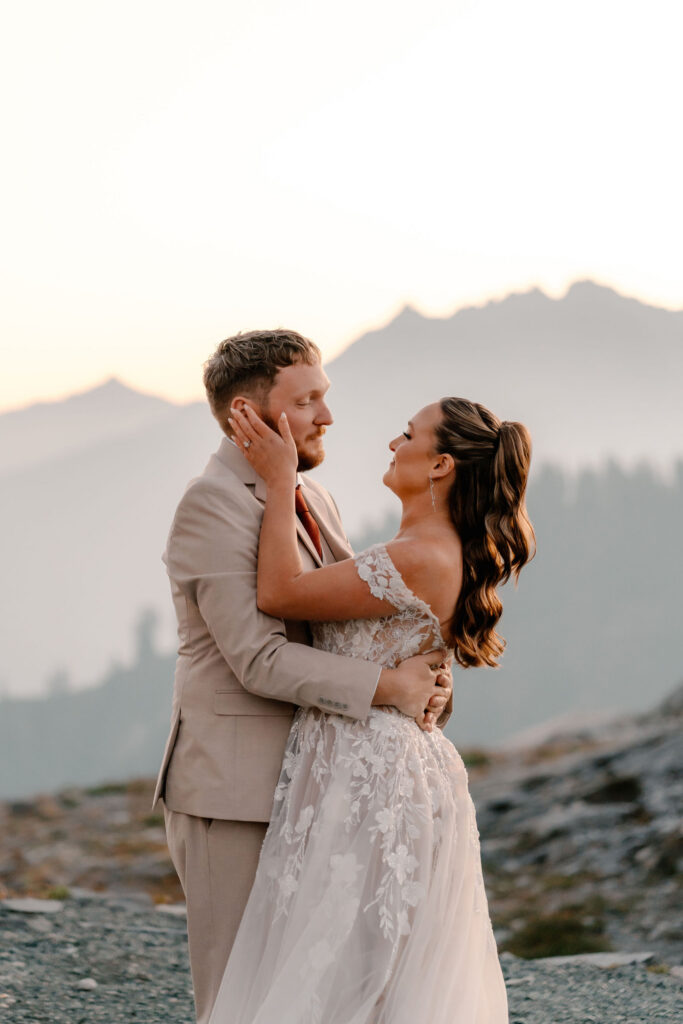 a bride holds her grooms face in her hand as they gaze lovingly into each others eyes 
