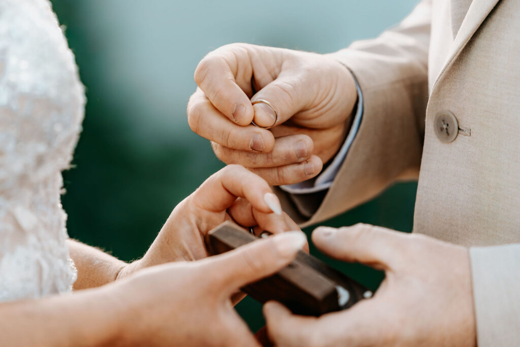a close up shot of a hands exchanging wedding rings 