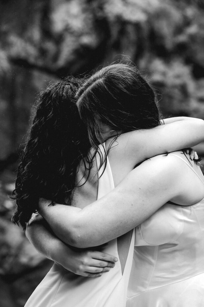 a tight black and white image of two brides embracing tightly 