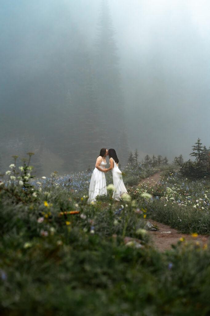 two brides kiss on a wildflower trail during their moody elopement 