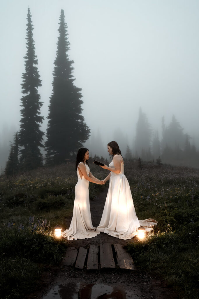 two brides exchange vows by lantern light in a foggy landscape 