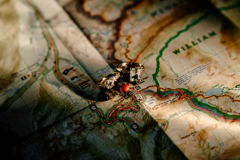 a detail shot of two wedding rings on a map of mount rainier 