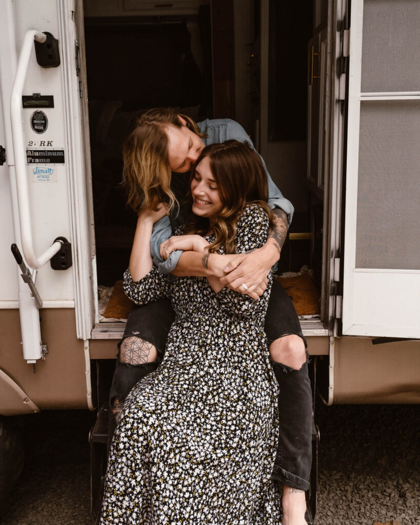 mount rainier elopement photographers embrace on the steps of their rv 