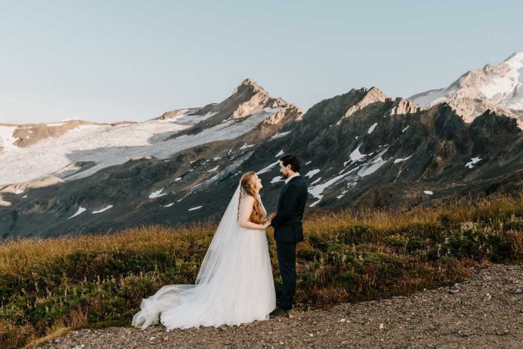 an early fall elopement in the cascades, We see a bride and groom exchanging vows with jagged peaks rising behind them