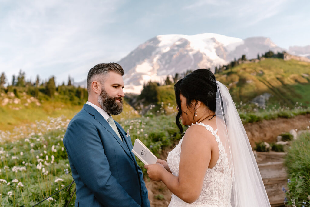 a close up image of a bride reading her vows to her groom. Mount rainier is soft behind them