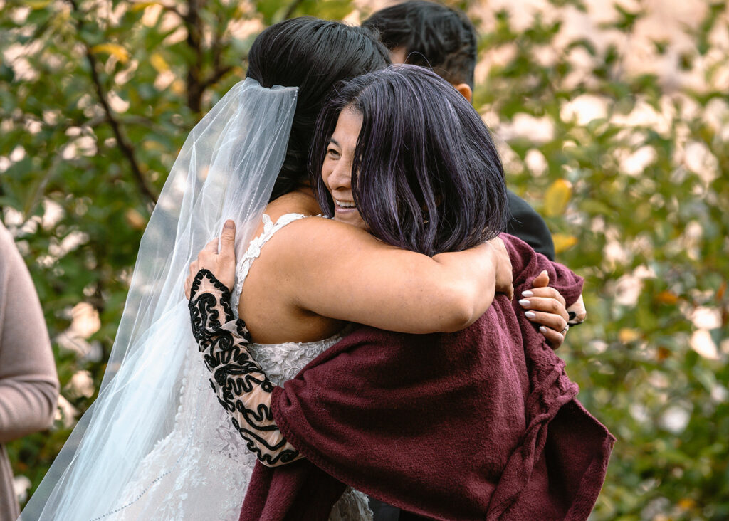 a bride hugs her mom who is smiling broadly after their micro wedding ceremony