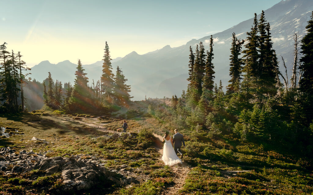 a bride and groom explore a trail in their wedding attire. Streaks of sunlight fill the frame.
