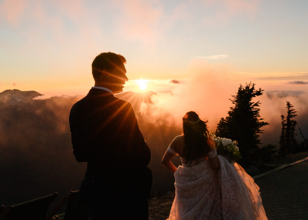 at the end of their elopement timeline, a couple looks out at a fiery sunset over the mountains