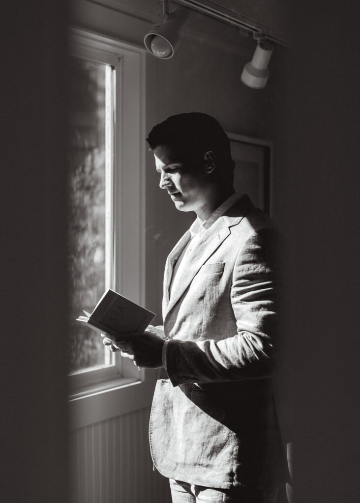 A black and white image of a groom reading over his vows for his coastal elopement. 