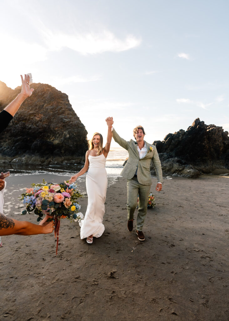 a bride and groom cheer as they begin to exit their coastal elopement ceremony