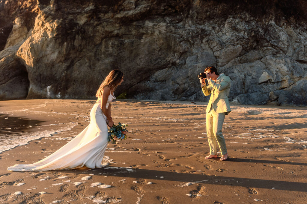 During their coastal elopement, a groom films his bride on a vintage super 8 camera as she runs around on the beach.