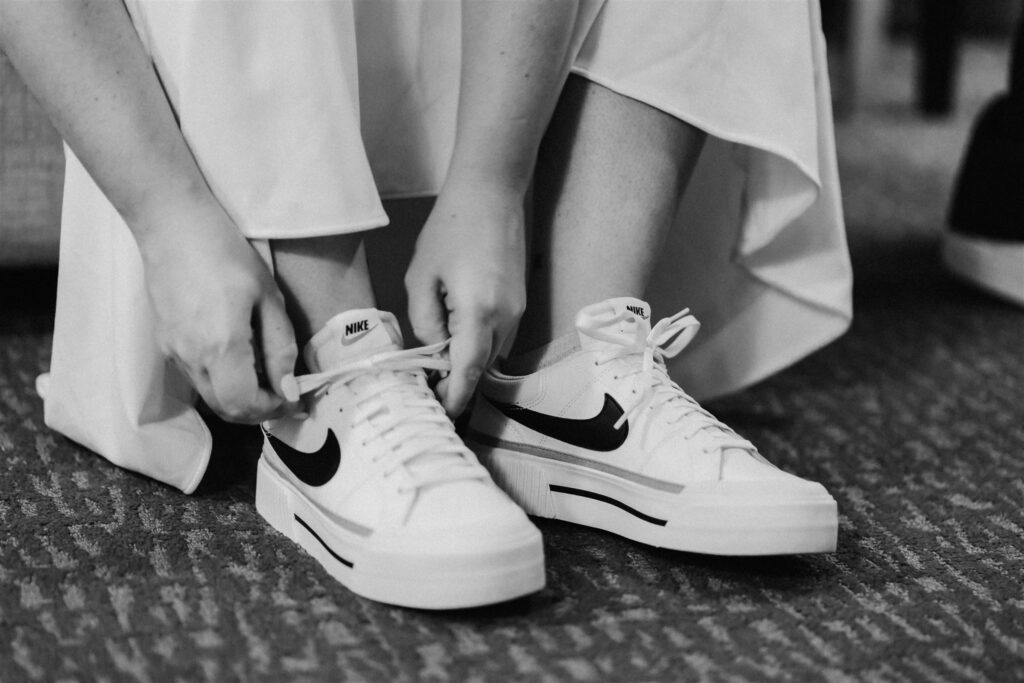 a bride laces up her Nikes, her chosen shoe for her pacific coast elopement. 