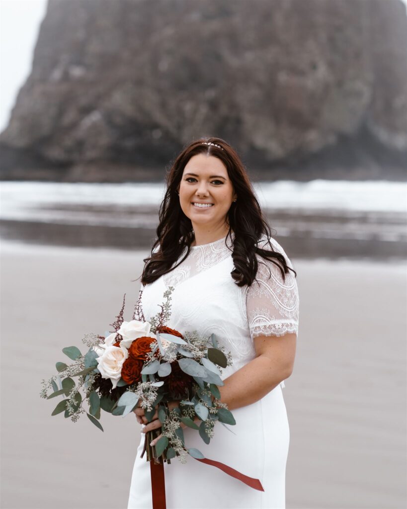 a bride holds her romantic bouquet and smiles at the camera during her pacific coast wedding