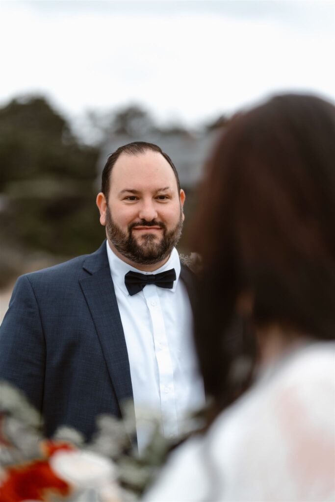a perspective shot of a groom gazing lovingly at his bride. his face is in focus and is framed by her silhouette during their pacific coast wedding 