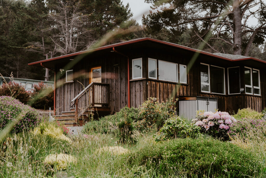 A wide shot off a coastal home framed by a bright garden, full of flowers and greenery.